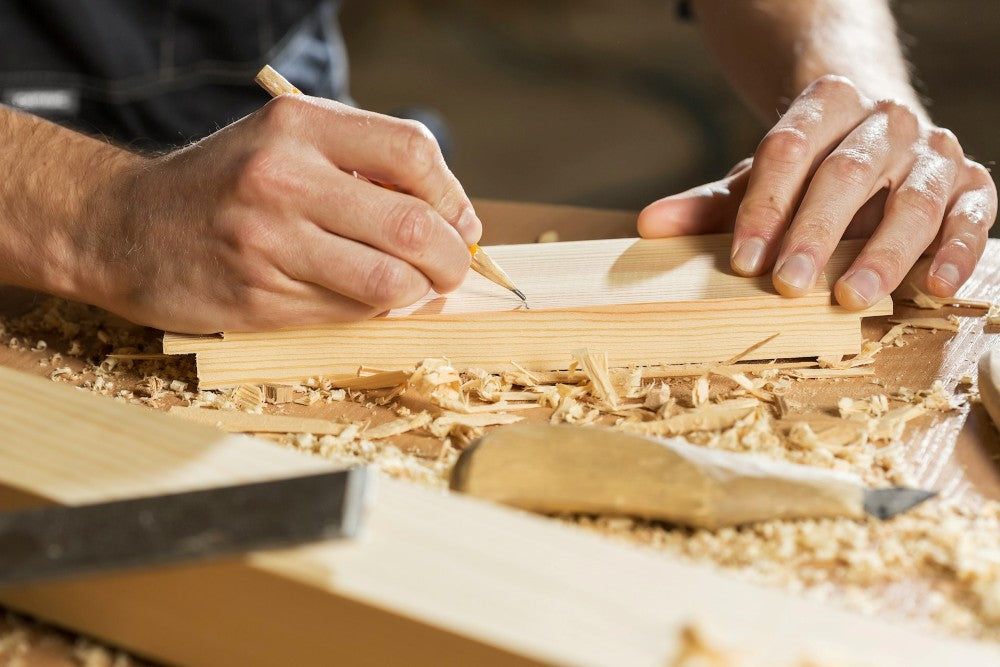 A man marking a piece of wood to be cut